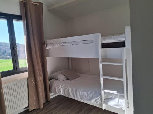 a couple of bunk beds in a room with a window at Les violettes du Bugey in Marchamp