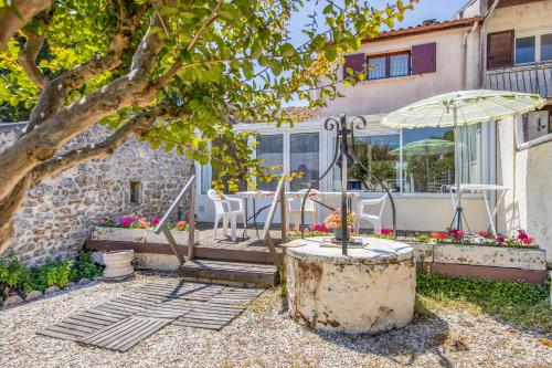 une maison avec un arbre et un parasol dans l'établissement Maison Place de l'Eglise, à Vendays-Montalivet
