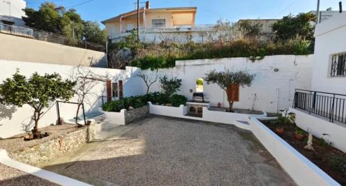 a courtyard with trees and a white wall at The White House - Aianteio in Aiándion