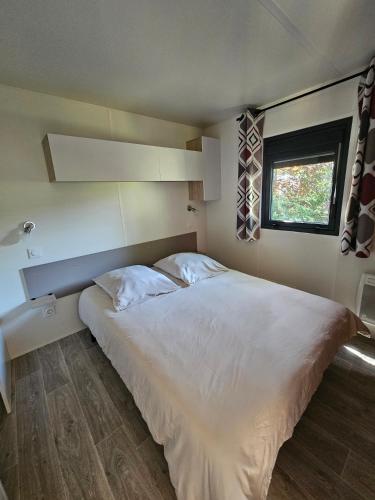 a large white bed in a room with a window at Camping de Charlieu in Charlieu