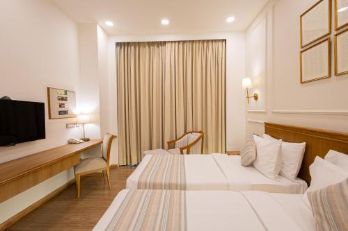 a hotel room with two beds and a desk at The BellaVista Hotel Chandigarh Panchkula in Chandīgarh