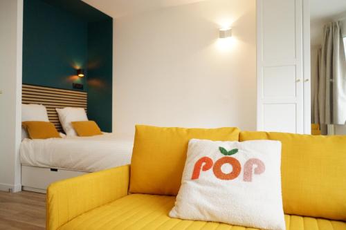 - un canapé jaune dans une chambre avec un lit dans l'établissement Pop Appart - Expo Paris Porte de Versailles - Balcon - Climatisation - Parking, à Paris