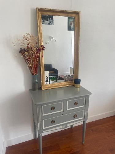 - une commode avec un miroir au-dessus dans l'établissement Appartement Buttes Chaumont, à Paris