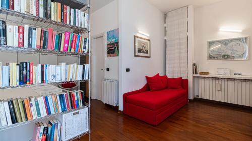a red chair in a room with books at Italianway - Tadino 1 A in Milan