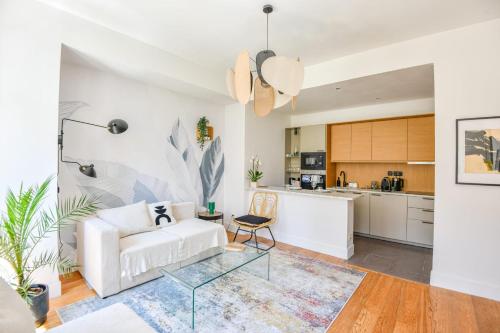 un salon avec un canapé blanc et une cuisine dans l'établissement Le Sainte - Appart 1 ch Vieux-Port hypercentre, à Marseille