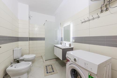 a bathroom with a toilet sink and a washing machine at Ivory Rose Apartment in Vlorë