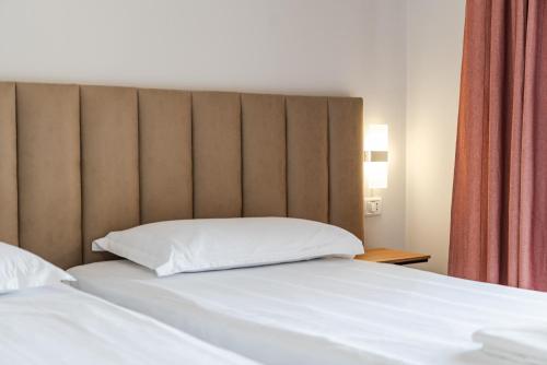 a bed with a large headboard in a room at Ivory Rose Apartment in Vlorë