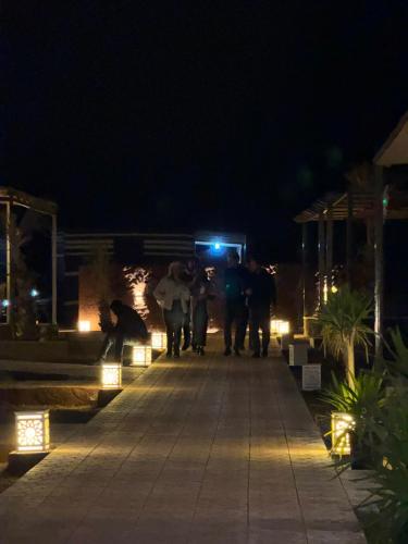 a group of people walking down a walkway at night at Wadi Rum Legend Luxury Camp in Wadi Rum