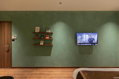 a flat screen tv on a green wall at Luxhome Mekong Hotel in Can Tho
