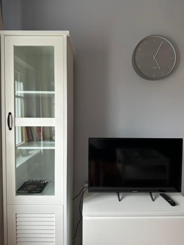 a tv and a clock on a wall next to a cabinet at Apartament Bankowy in Olecko
