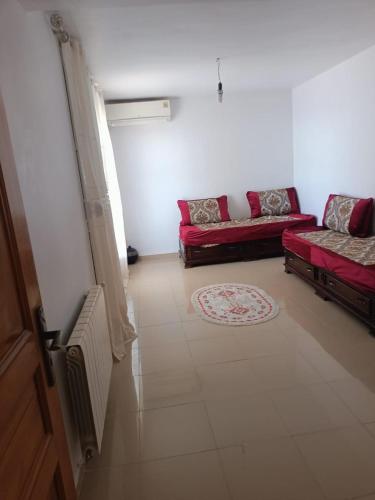 a living room with a red couch and a rug at Triplex à Bou Ismaïl près de la plage in Bou Ismaïl