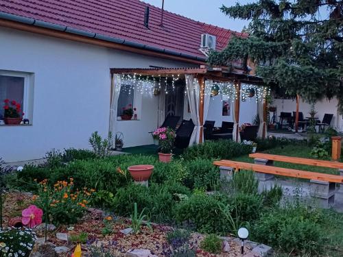 a garden in front of a house with a bench at Százszorszép Vendégház in Csongrád