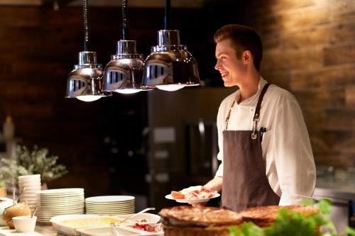 a chef standing in a kitchen with a plate of food at SEETELHOTEL Kaiserstrand Beachhotel das Lifestyle-Hotel direkt am Strand in Bansin
