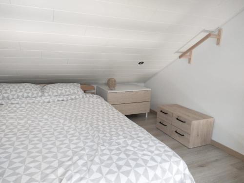 a bedroom with a white bed and a wooden dresser at Studio À la Lorette in Rochefort