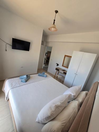 a bedroom with a white bed and a tv at Villa Papa in Ksamil