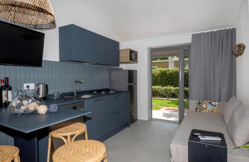 a kitchen and living room with blue cabinets at Camping Village Baia Azzurra in Castiglione della Pescaia