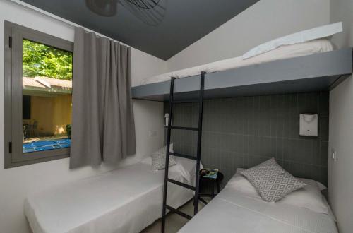 a bedroom with two bunk beds and a window at Camping Village Baia Azzurra in Castiglione della Pescaia