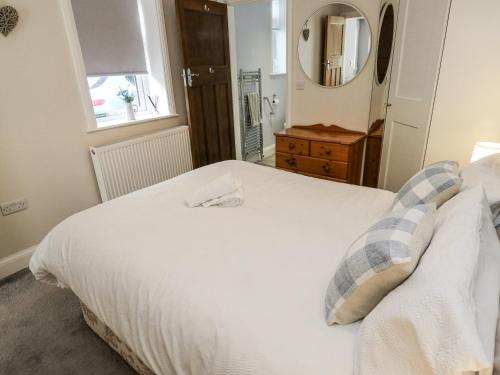 a bedroom with a white bed and a mirror at Little Birchinlea in Glossop
