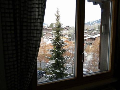 a view of a christmas tree from a window at Central Location Cozy 3 BR Flat in Gstaad in Gstaad