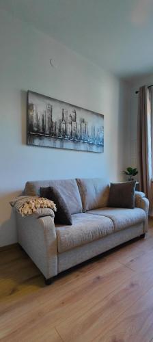 a couch in a living room with a painting on the wall at Cozy Studio, Convenient, Close to nature & sea in Helsinki