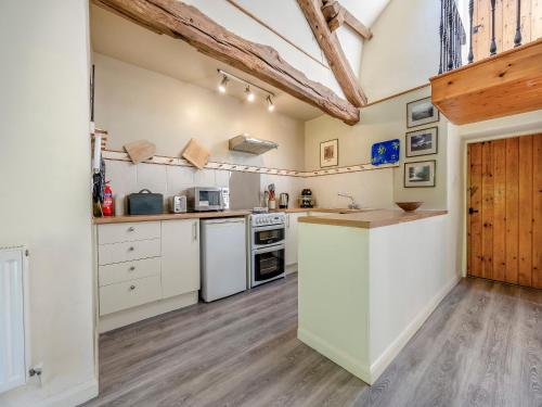 a large kitchen with white appliances and wooden floors at Mill Barn in Askham