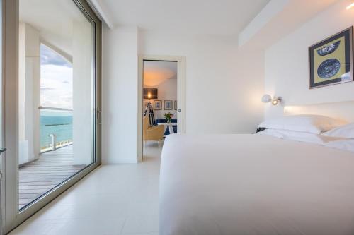 a white bedroom with a view of the ocean at Excelsior Hotel, SPA & Lido - Preferred Hotels & Resorts in Pesaro