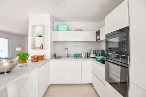 une cuisine blanche avec des armoires et des appareils blancs dans l'établissement Le Prado - Appart haut standing 2 ch avec terrasse, à Marseille