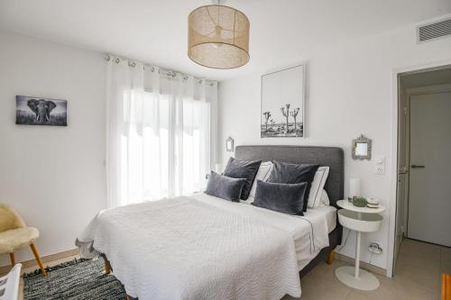 une chambre blanche avec un lit et une chaise dans l'établissement Le Prado - Appart haut standing 2 ch avec terrasse, à Marseille