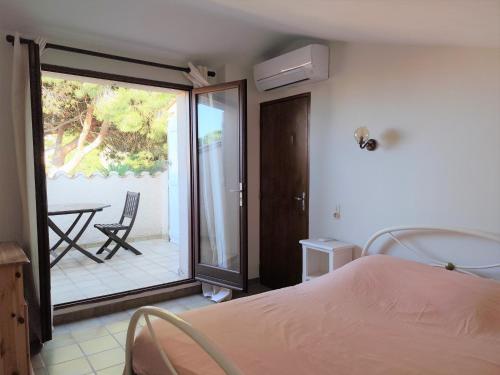 une chambre avec un lit et un balcon avec une table dans l'établissement Villa et jardin de charme, à 5 mn de la plage, au Barcarès