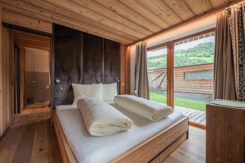 a bedroom with a bed with pillows and a window at Mountainlodge Luxalpine in San Vigilio Di Marebbe