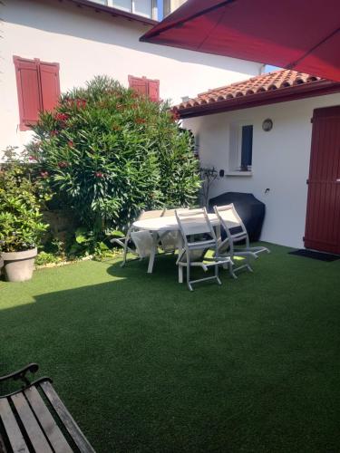 a patio with a table and chairs on a lawn at Pinpirinia min 3 nuits in Guéthary