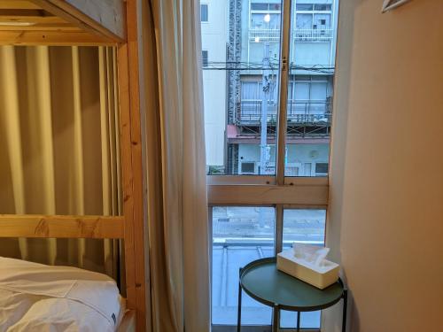 a bedroom with a window with a bed and a table at Tomarotto Hostel in Takayama