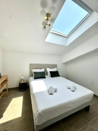 Un dormitorio con una gran cama blanca con tragaluz. en Duplex en résidence, en Propriano
