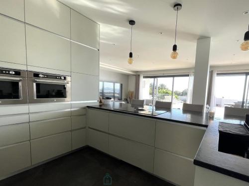 une cuisine avec des armoires blanches et un comptoir noir dans l'établissement Villa Baverde Luxury, à Istres