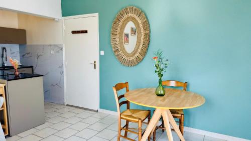 une table avec un vase de fleurs sur un mur bleu dans l'établissement Esprit Opale - Appartement avec terrasse à 2 pas de la mer, à Merlimont
