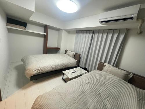 a small room with two beds and a window at CAlMU ASAKUSA HOTEL ASAKUSA UENO IMADOZINZYA TOKYOSKYTREE HANEDA NARITA GINZA TOKYOSTATION Direct 浅草上野東京スカイツリー 成田空港羽田空港東京駅直行バス 電車便利 in Tokyo