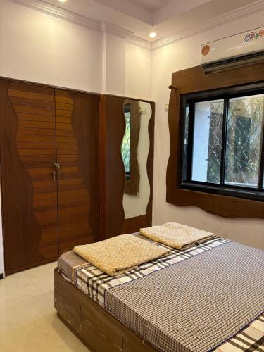a bedroom with a bed with a wooden headboard and a window at Jasmine Villa in Thane best place to chill in Thane