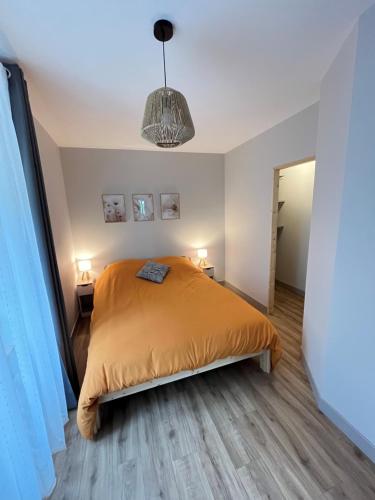 une chambre avec un lit avec un couvre-lit orange dans l'établissement La Petite Reine de l'Abbaye, à Thiers