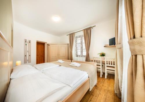 a bedroom with a large white bed and a table at Hotel Barbakan in Český Krumlov