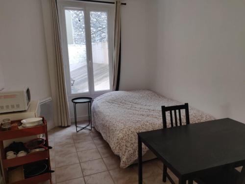 une chambre avec un lit, une table et une fenêtre dans l'établissement Studio à 2 pas du métro, à Paris