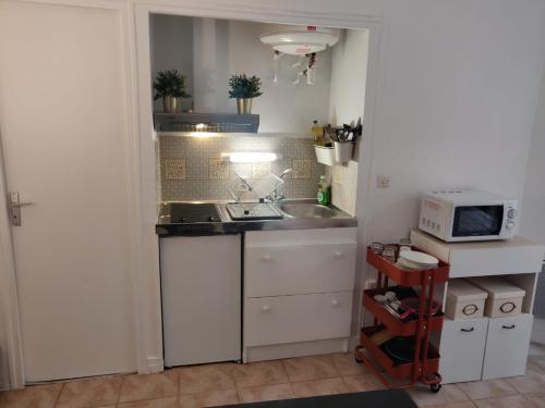 une petite cuisine avec un évier et un micro-ondes dans l'établissement Studio à 2 pas du métro, à Paris