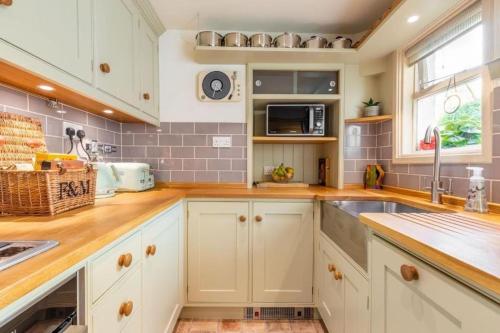 une cuisine avec des armoires blanches et un évier dans l'établissement Historic King's Lynn Gem with Walled Garden, à King's Lynn