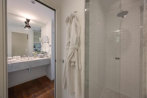 a white bathroom with a shower and a sink at Excelsior Hotel, SPA & Lido - Preferred Hotels & Resorts in Pesaro