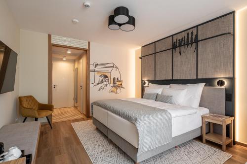 a bedroom with a large white bed and a chair at Malom és Kacsa Boutique Hotel in Tata