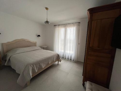 une chambre blanche avec un lit et une fenêtre dans l'établissement Maison dans un hameau avec piscine, à Gordes