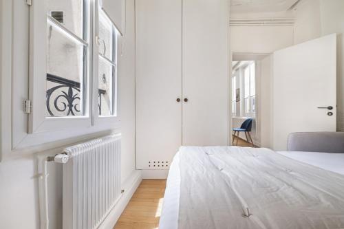 une chambre blanche avec un lit et une fenêtre dans l'établissement Vita, à Paris