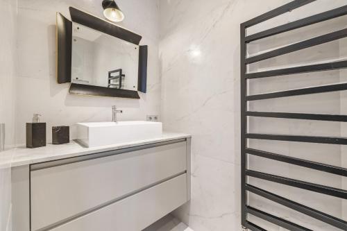 une salle de bain blanche avec un lavabo et un miroir dans l'établissement Vita, à Paris