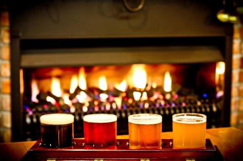 three glasses of beer in front of a fireplace at Rutland Arms Inn in Whanganui