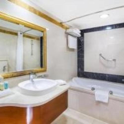 a bathroom with a sink and a tub and a mirror at Holiday International Hotel Embassy District by CMG in Dubai