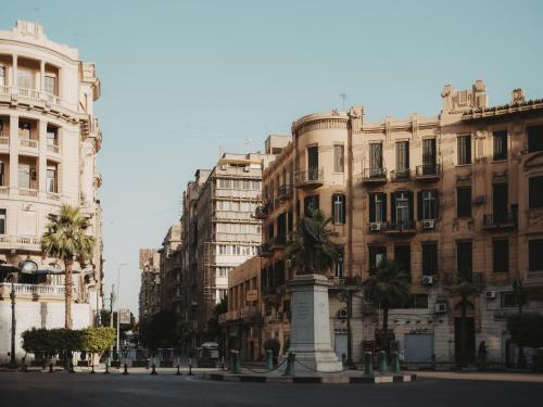 a city street with tall buildings and a monument at Brassbell l DT l Hannaux l Tahrir sq in Cairo